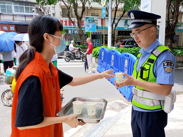 ▲志愿者为值守高考路口的交警送上消暑饮品.jpg